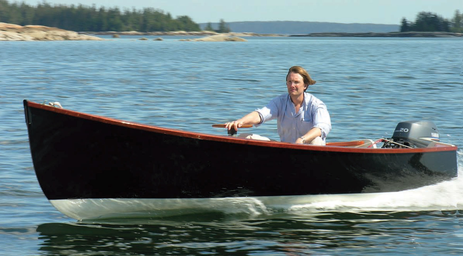 Man pilots Jericho Bay Lobster Skiff motorboat on the water.