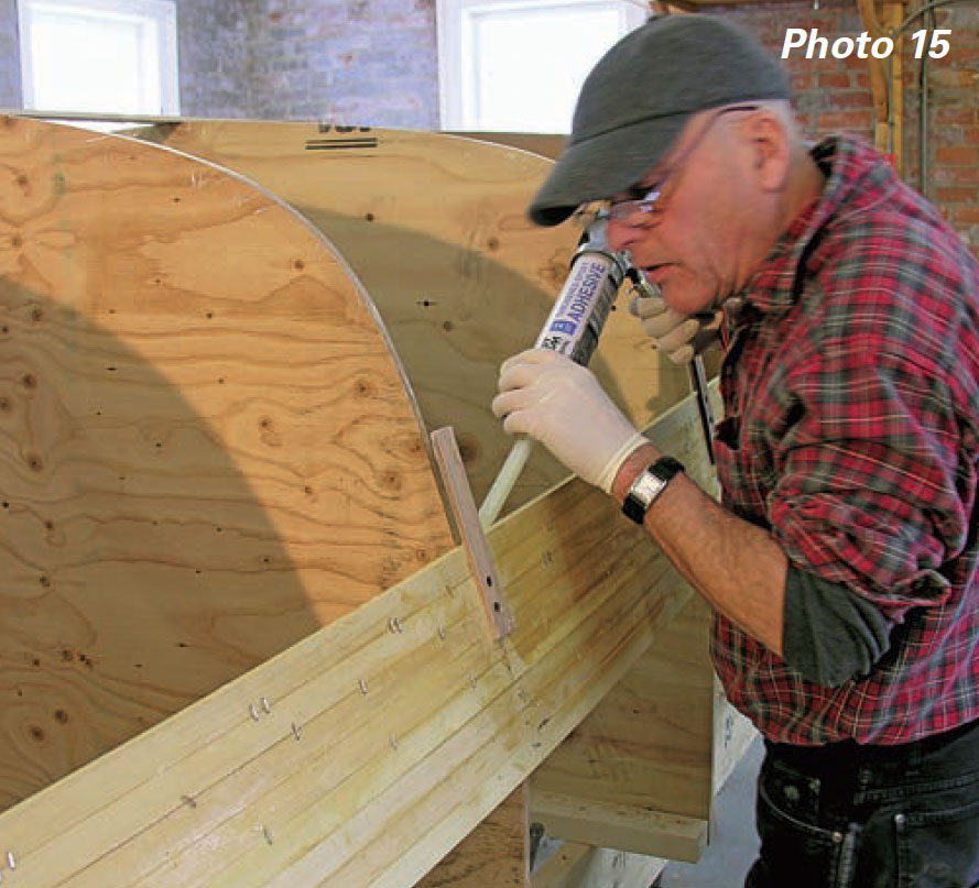 Man uses caulking gun to apply epoxy to boat planks.