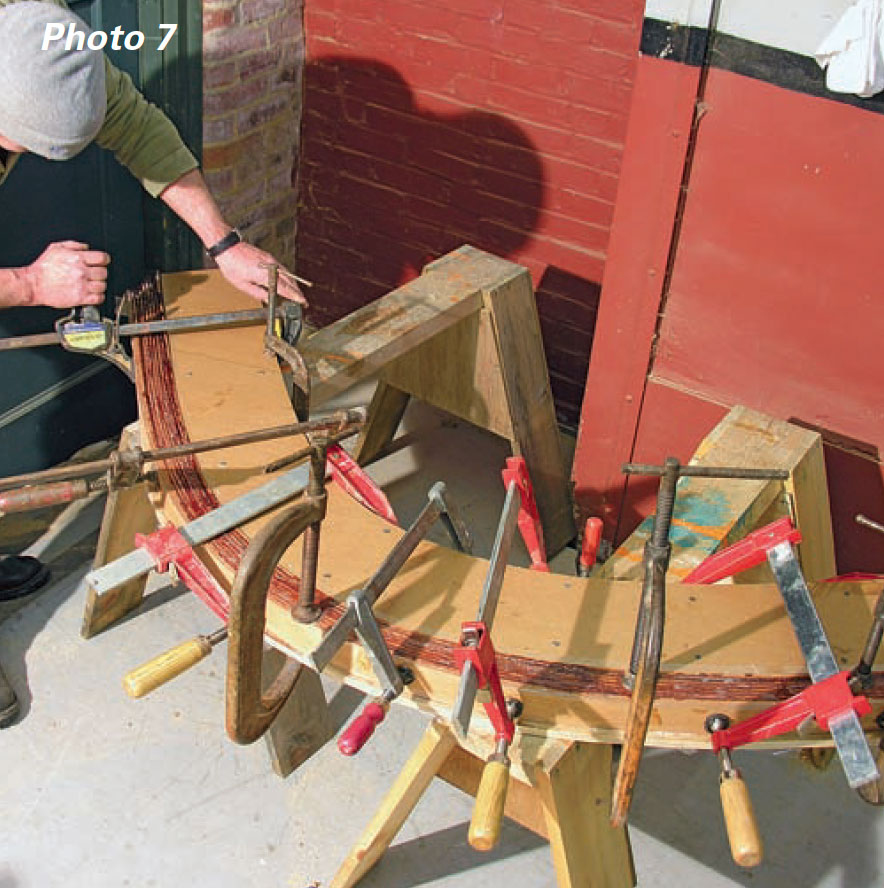 Man uses several clamps to hold wood together.