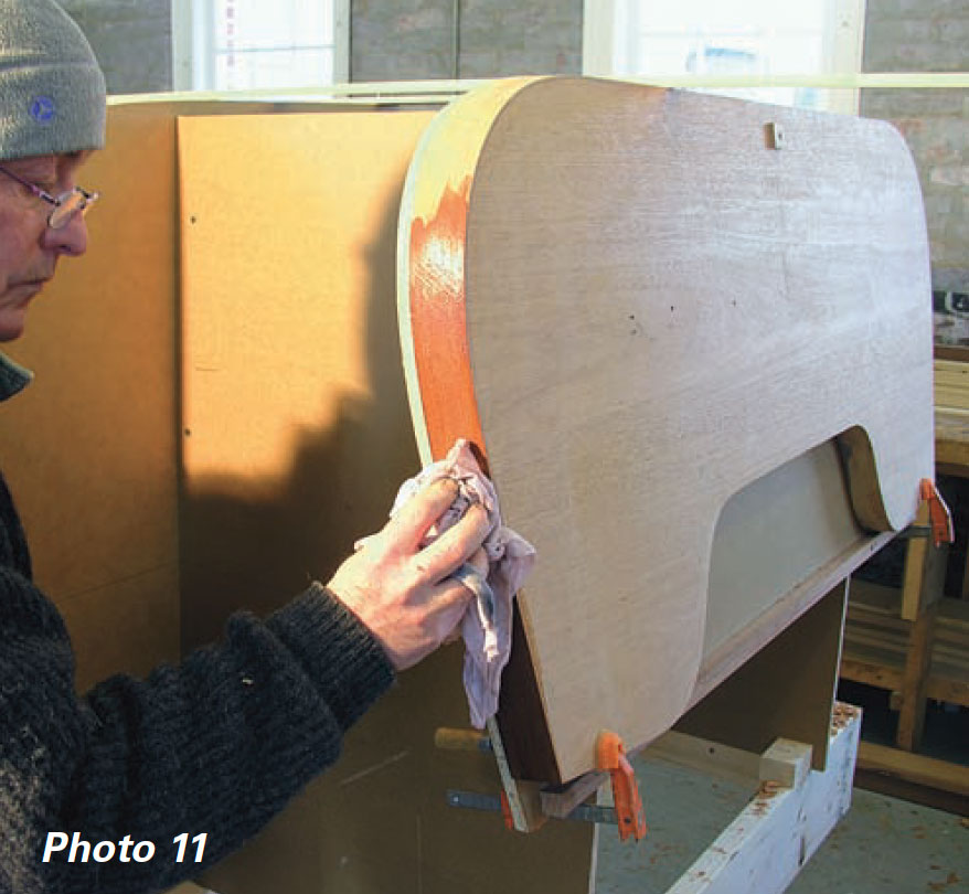 Man uses a wet rag to dampen the end-grain of a transom.