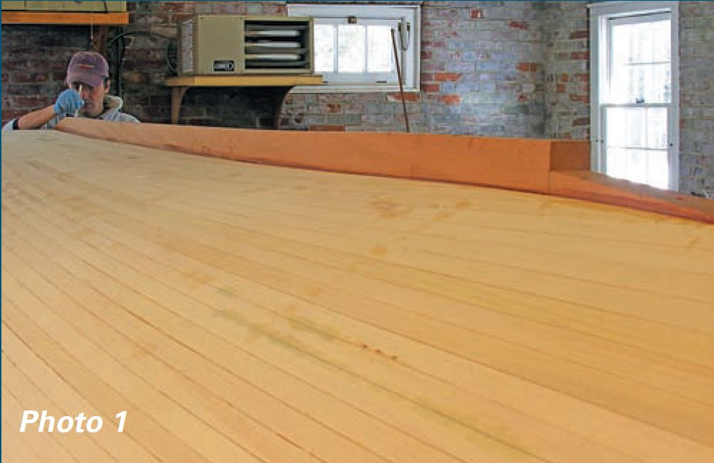 Man eyes the bottom of a wooden boat.