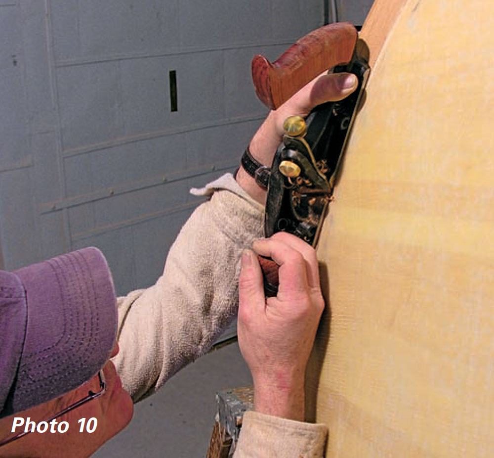 Man uses rabbit plane to trim wood from boat planking.