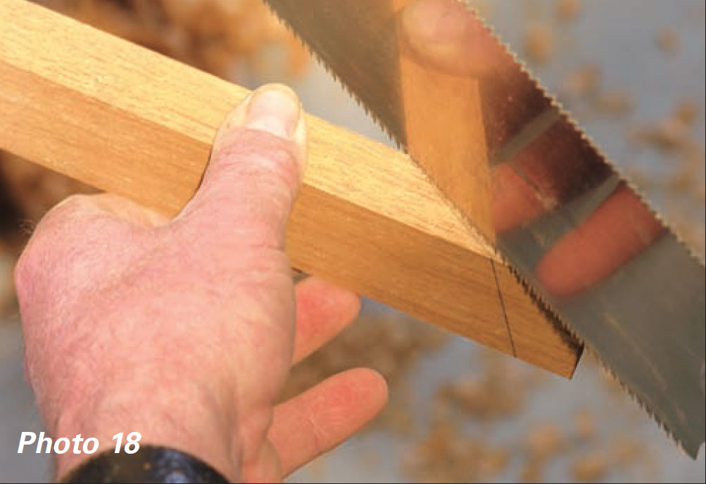 Hand holds a marked piece of wood to a saw blade.