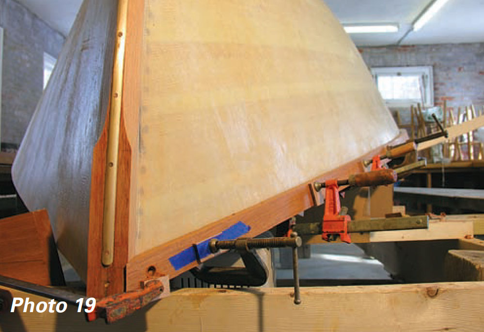 Upside down wooden boat with guardrails held in place by metal clamps.