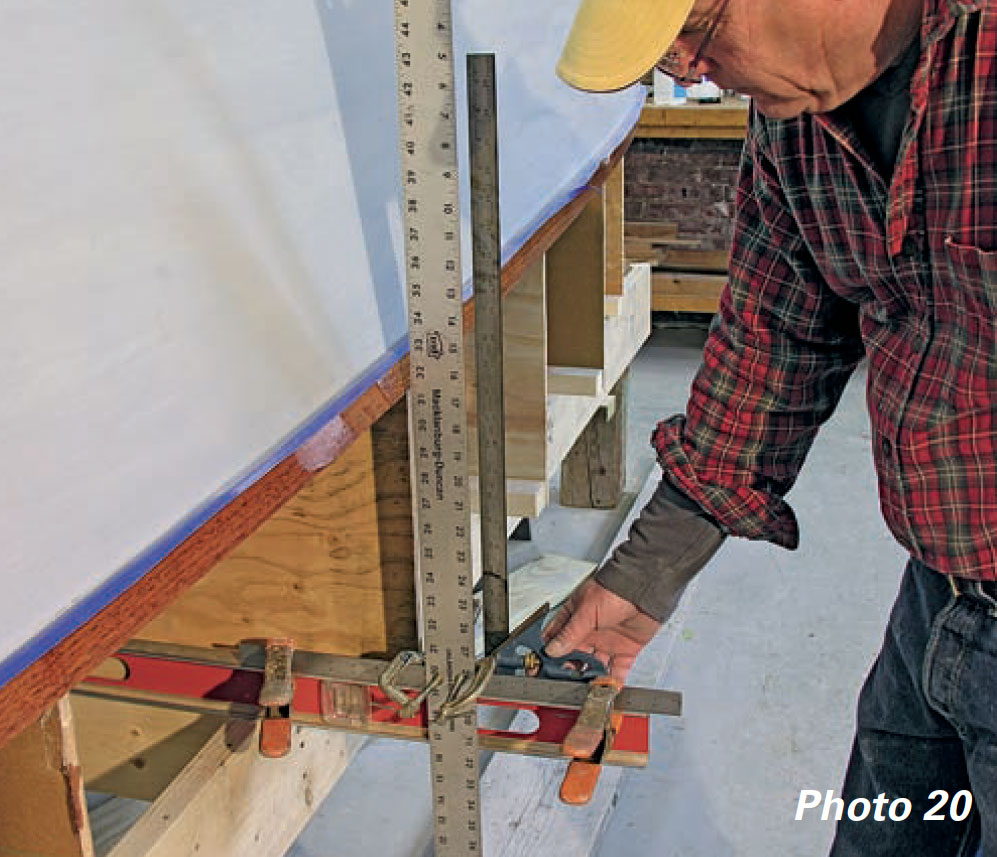 Man uses straightedge to mark a boat's waterline.