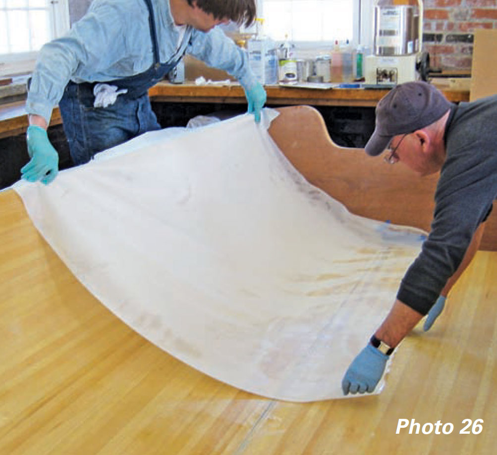 Boatbuilders apply release fabric over a boat's inner hull.