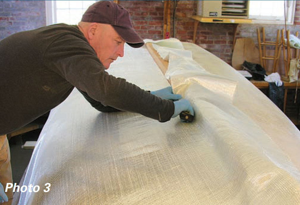 Boatbuilder trims fiberglass fabric.