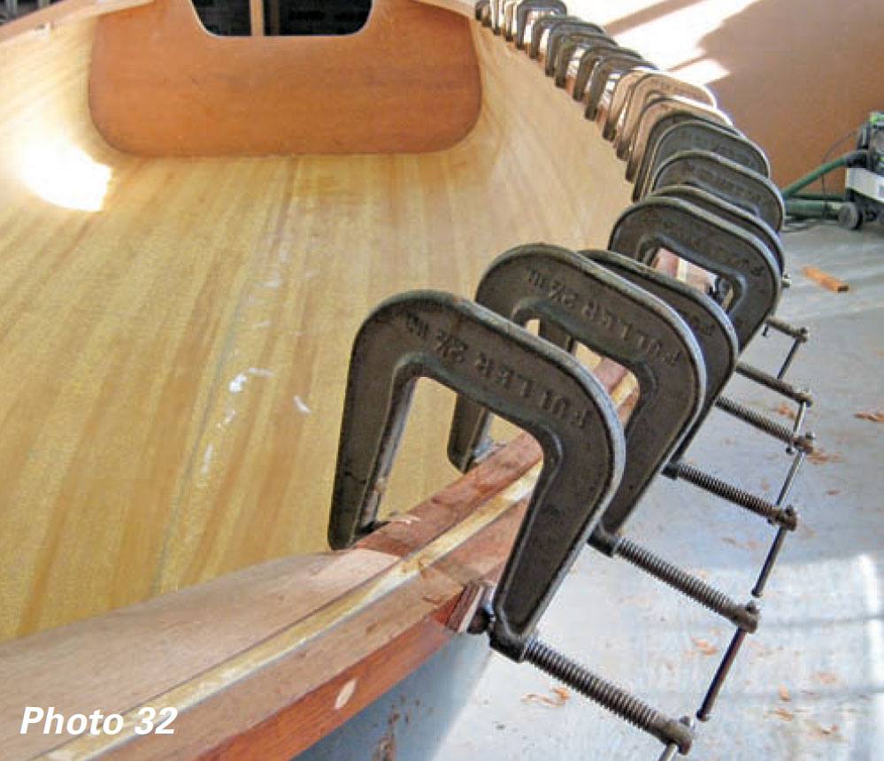 A boat's guardrail is held in place with epoxy and several metal clamps.