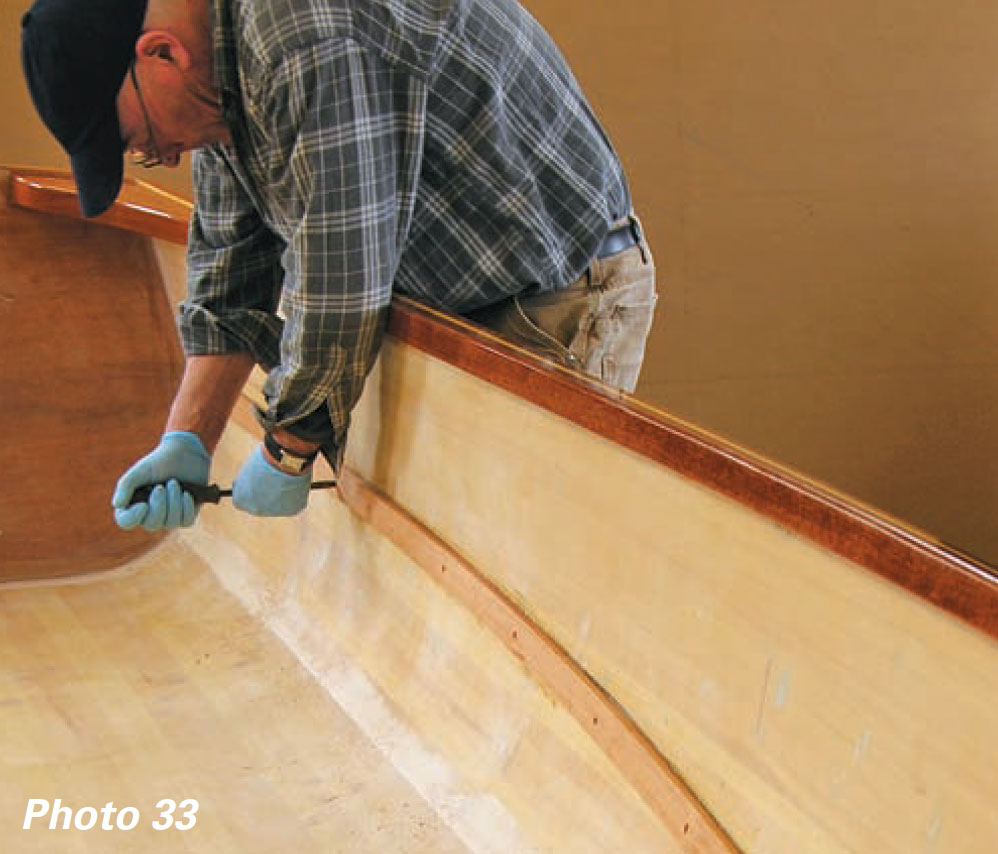 Man uses screwdriver to attach a boat's seat riser inside the hull.