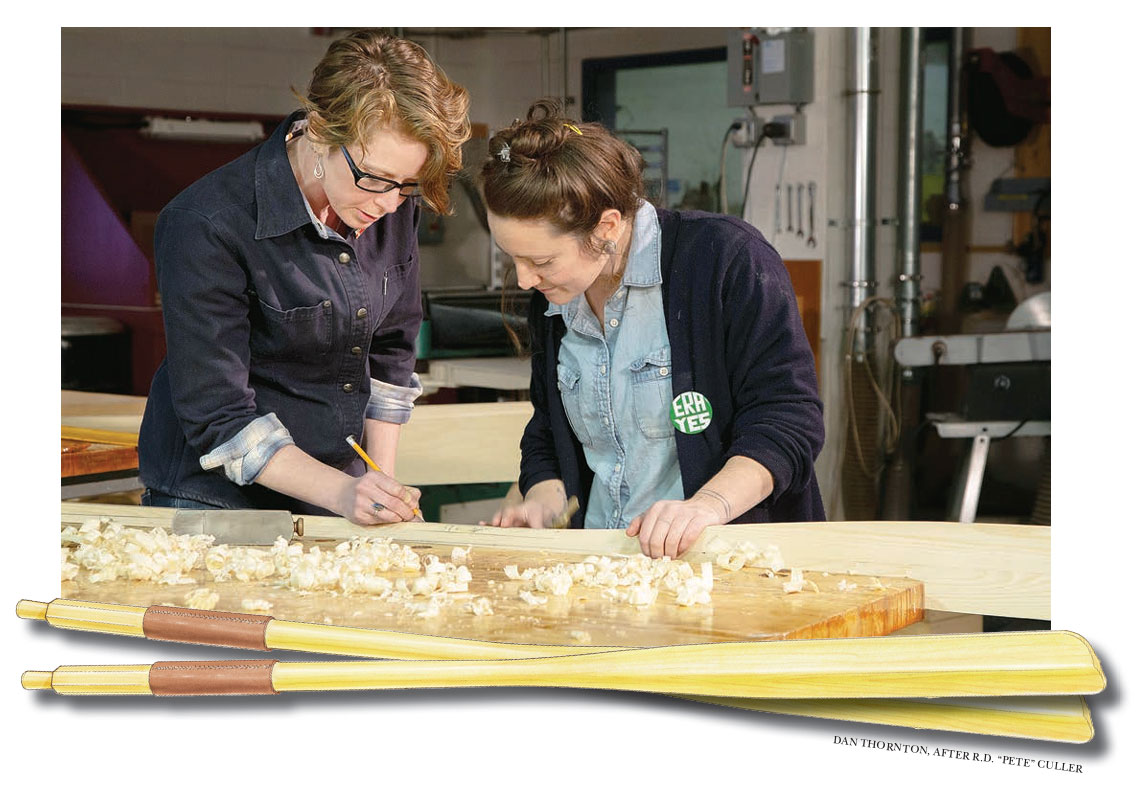 Two women make marks on a wooden oar with a pencil.