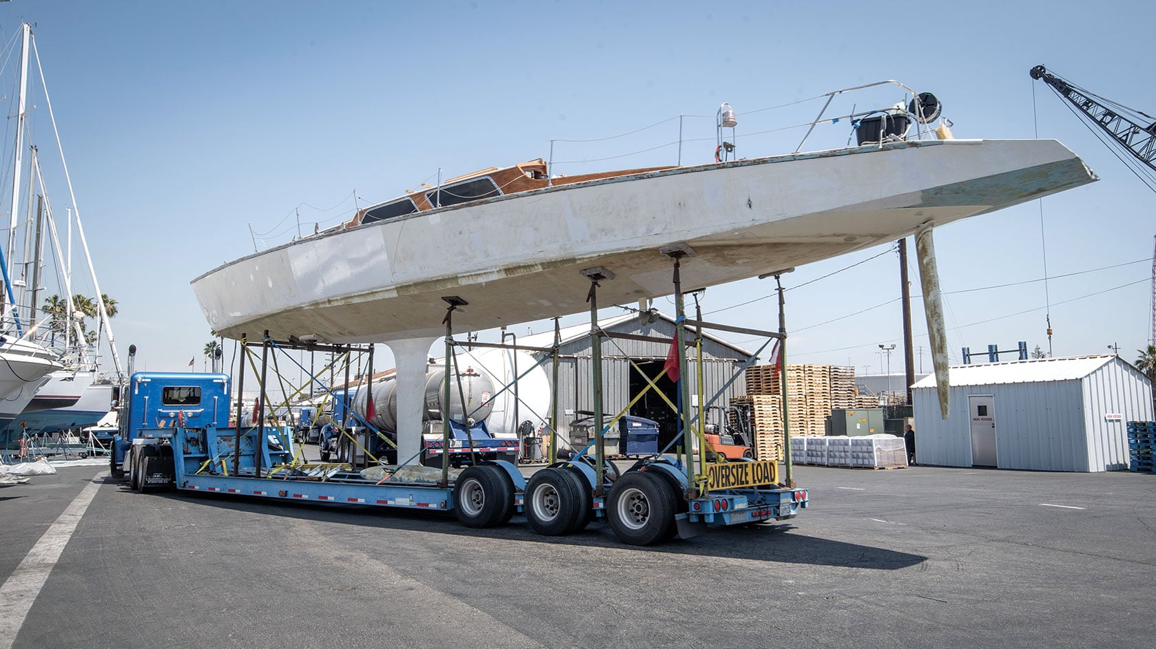 Large white yacht hull loaded on an oversize load truck.