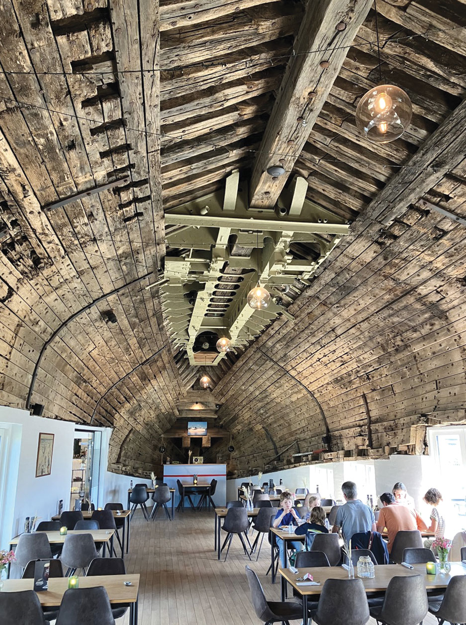 Diners enjoy a meal inside the wooden hull of a former large fishing boat.