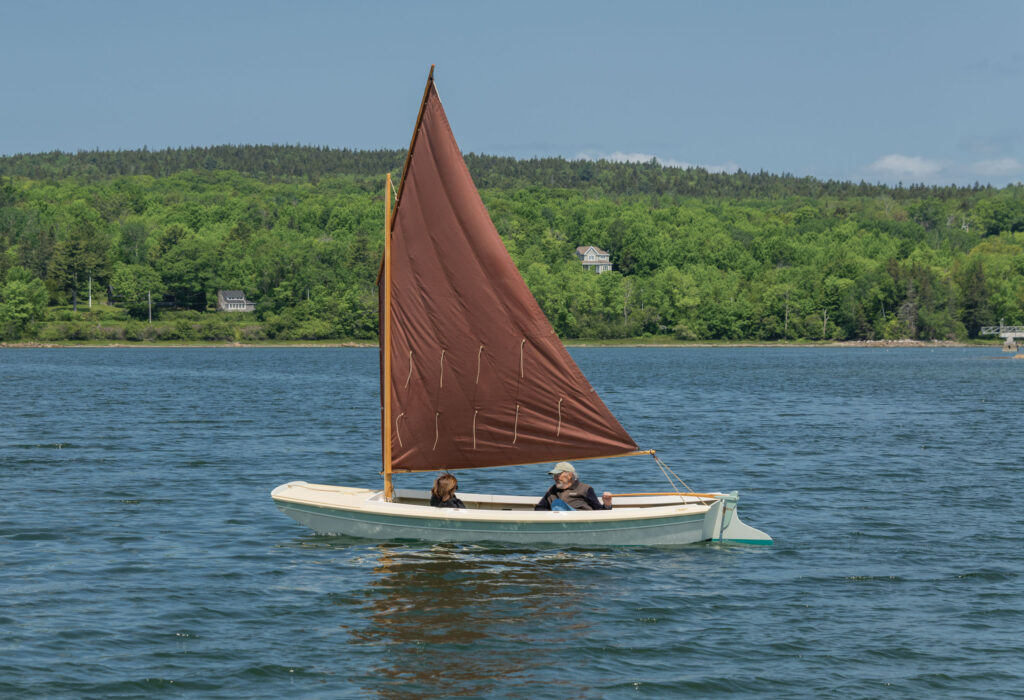 Man and woman in a small sailboat on the water.