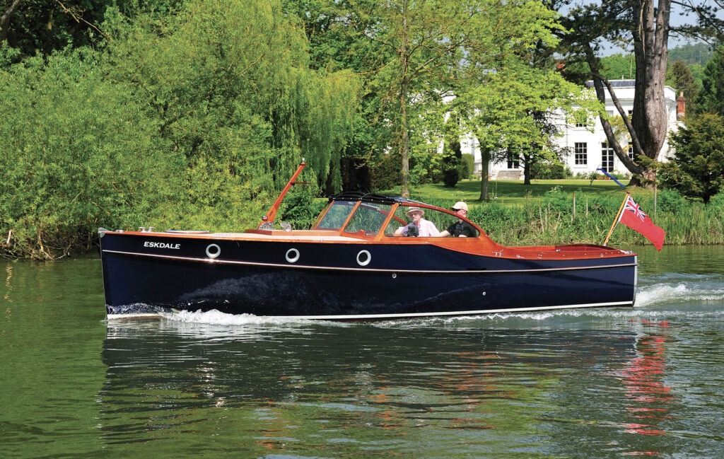 A Bristol 27 with shiny black topsides and a bright deck glides through the river.
