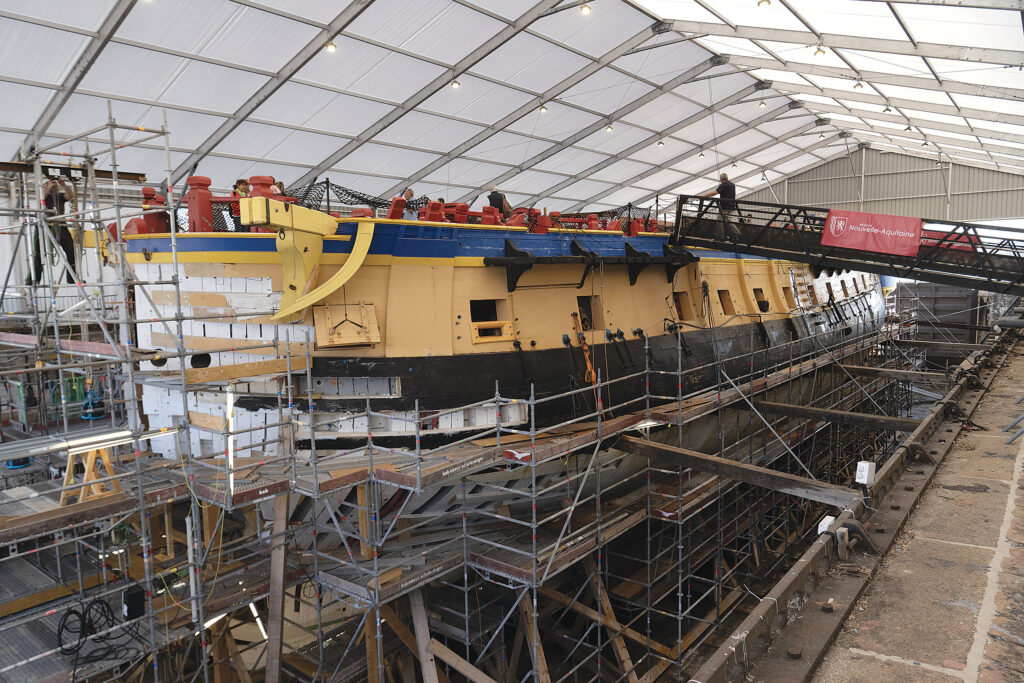 L’HERMIONE frigate dry-docked in a warehouse.