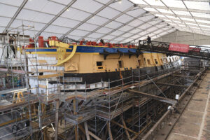 L’HERMIONE frigate dry-docked in a warehouse.